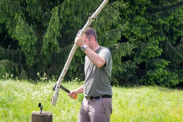 Person schlägt mit einem Stock auf einen Holzblock