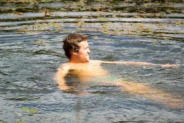 Person schwimmt in einem Gewässer mit Wasserpflanzen