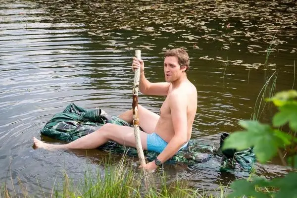 Person sitzt auf einer selbstgebauten Flotte im Wasser