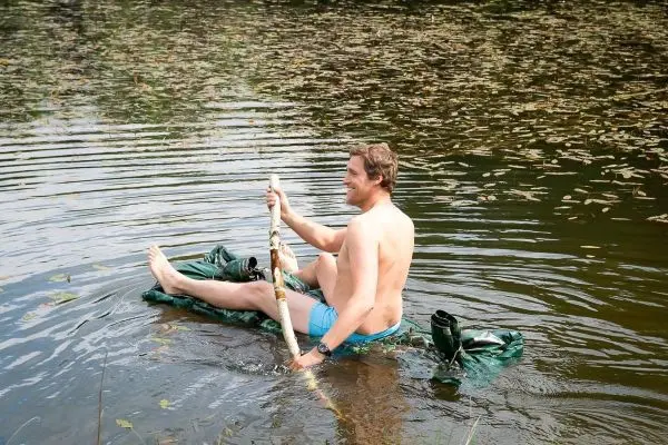 Person sitzt auf einer selbstgebauten Schwimmhilfe im Wasser