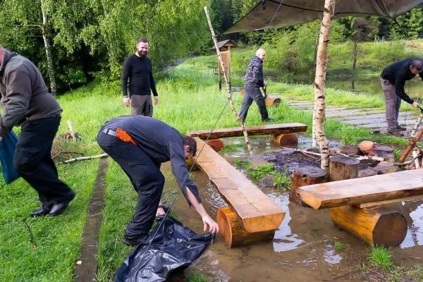 Personen richten eine Tarp-Notunterkunft über einer nassen Fläche ein
