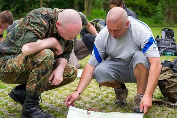 Zwei Personen studieren eine Karte auf dem Boden im Freien