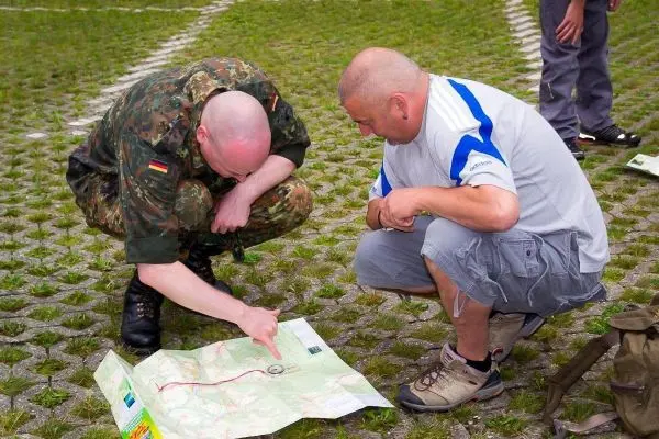 Zwei Personen studieren eine Karte auf dem Boden und zeigen auf einen Punkt