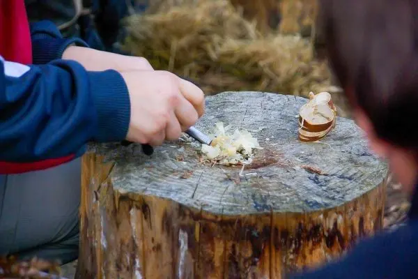 Ein Messer schabt Holzspäne von einem Baumstumpf