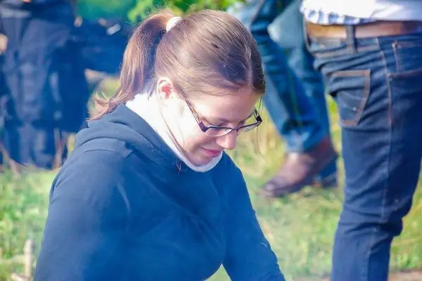 Frau sitzt am Boden und konzentriert sich auf ein kleines Feuer