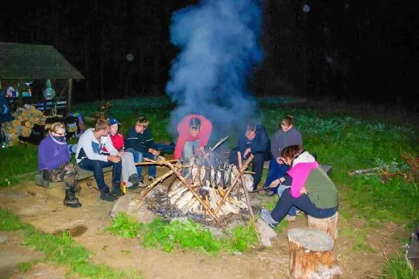 Grillspieße mit Fisch über einem offenen Feuer, Rauch steigt auf