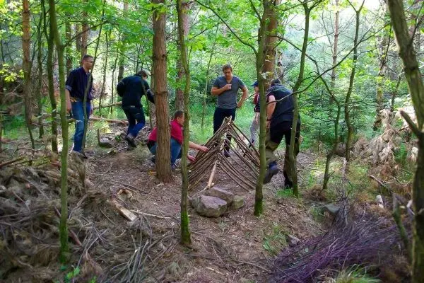 Gruppe baut eine Tarp-Notunterkunft aus Ästen im Wald
