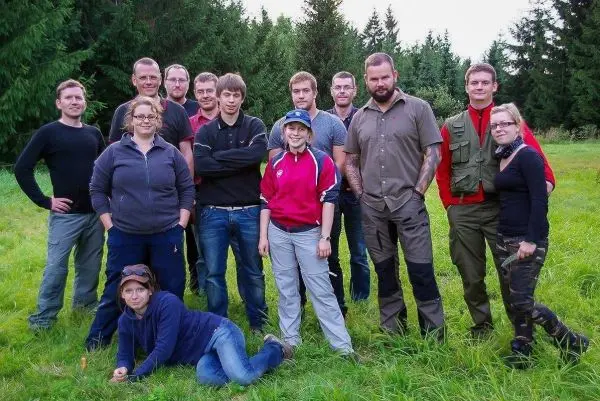 Gruppierung von Personen in einer Wiese, umgeben von Bäumen