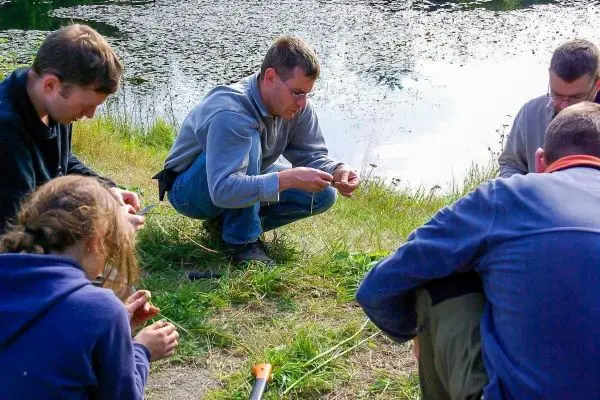 Gruppierung von Personen kniet am Ufer und bearbeitet Materialien
