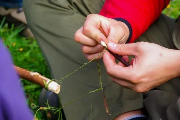 Hände flechten eine Schnur aus Pflanzenmaterialien