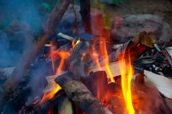 Kleine Flamme lodert zwischen Holzstücken im Feuer