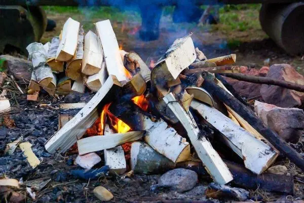 Kleine Flamme mit glühenden Holzstücken und Rauchentwicklung