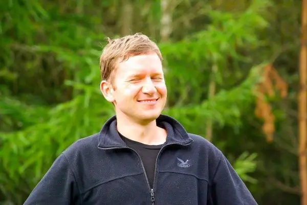 Lächelnde Person steht in der Natur mit geschlossenen Augen