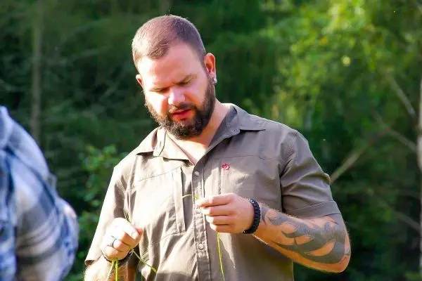 Mann hält Gräser in der Hand und konzentriert sich auf eine Tätigkeit
