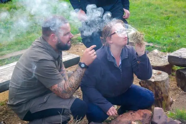 Person zeigt einer anderen Person, wie man Feuer macht beim Survival Training