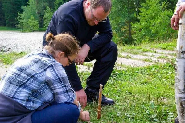 Zwei Personen arbeiten an einer Holzhebel-Konstruktion im Freien