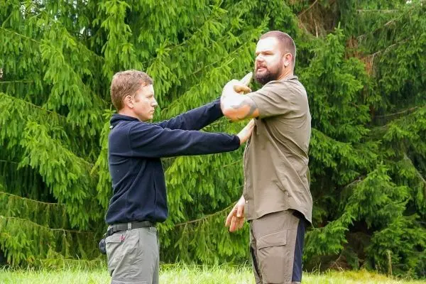 Zwei Personen üben eine Selbstverteidigungstechnik im Freien
