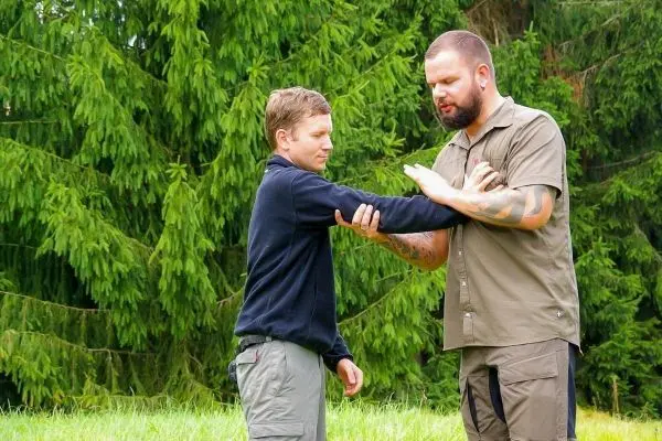 Zwei Personen üben eine Technik zur Armkontrolle im Freien