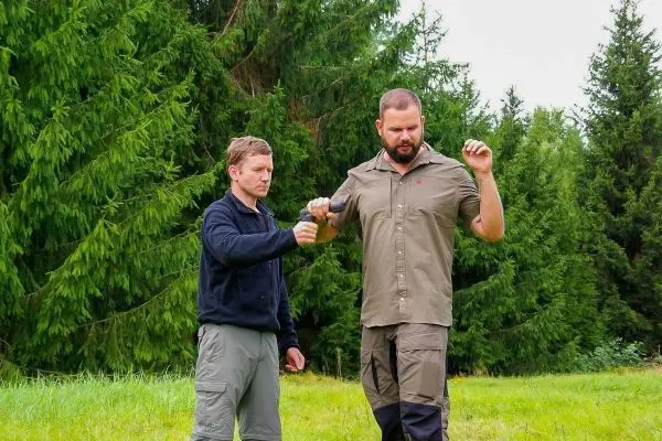 Zwei Personen üben eine Technik zur Handhabung eines Werkzeugs im Freien