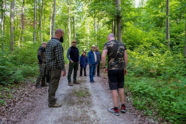 Gruppe steht auf einem Waldweg und diskutiert in einer grünen Umgebung