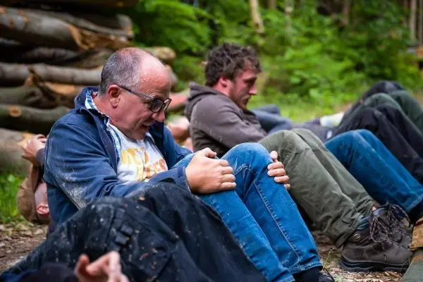 Gruppenteilnehmer führen Übungen im Sitzen durch, Rücken an Rücken auf dem Boden