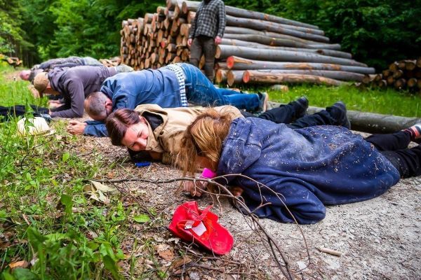 Gruppenteilnehmer liegen am Boden und üben eine Technik zur Tarnung
