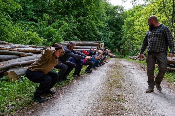 Gruppentraining mit mehreren Personen in Hockstellung entlang eines Waldweges