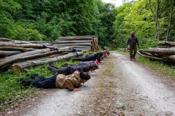 Gruppentraining mit mehreren Personen in Liegestützposition auf einem Waldweg