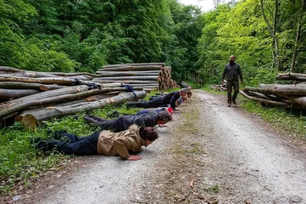 Gruppentraining mit mehreren Personen in Liegestützposition auf einem Waldweg
