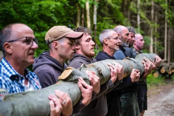 Gruppierung hebt gemeinsam einen langen Baumstamm an