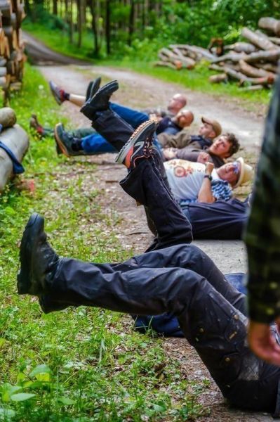 Gruppierung von Personen in liegender Position auf einem Waldweg, Beine angehoben