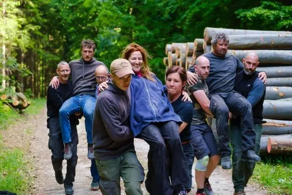 Gruppierung von Personen trägt einen anderen Teilnehmer auf einem Waldweg