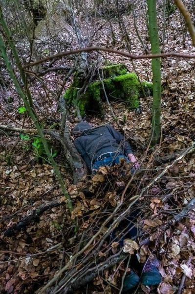 Im Unterholz liegen Äste und Laub, ein Körper ist teilweise verdeckt