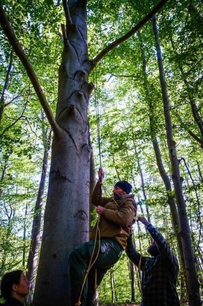 Mann klettert an einem Seil hoch, während eine andere Person das Seil hält