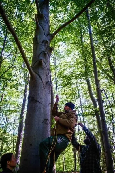 Mann klettert an einem Seil hoch, während eine andere Person das Seil hält