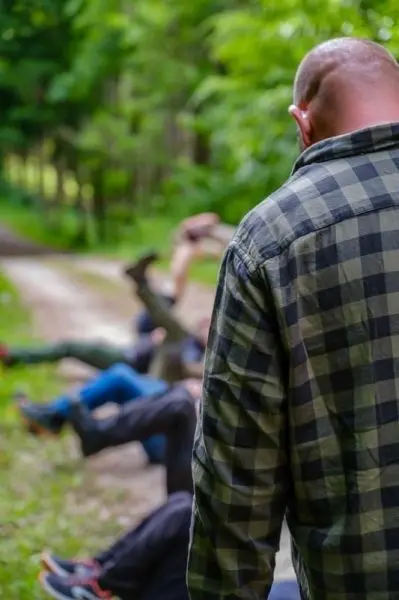 Person in kariertem Hemd beobachtet andere, die am Boden liegen
