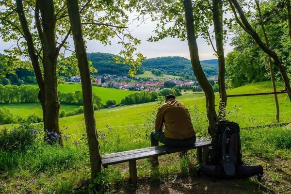Person sitzt auf einer Bank und schaut auf die Landschaft