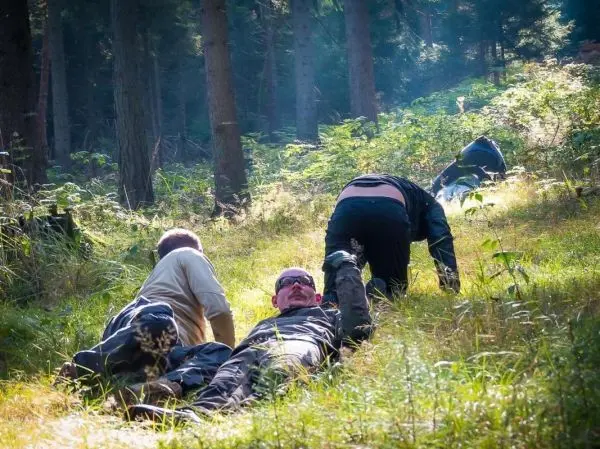 Drei Personen liegen im Gras und führen eine Übung im Gelände durch