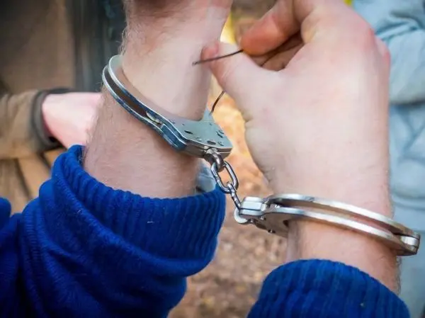 Hände mit Handschellen versuchen, sich mit einem Draht zu befreien