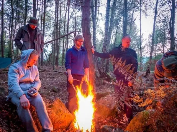 Kleines Bodenfeuer brennt zwischen mehreren Personen im Wald