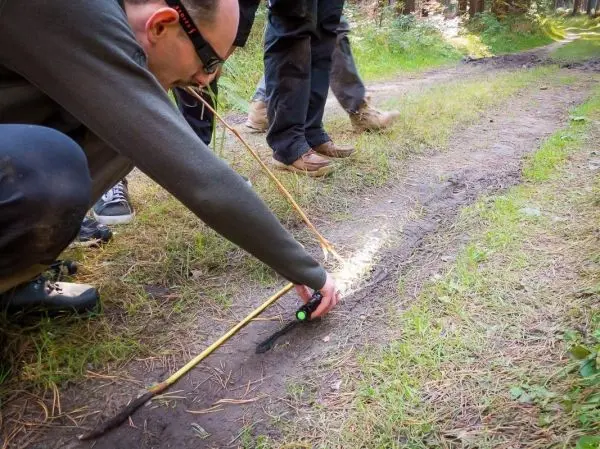 Kompass wird auf dem Boden ausgerichtet, während eine Schnur gespannt wird