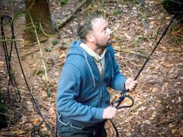 Mann zieht an einem Seil in einem Waldgebiet
