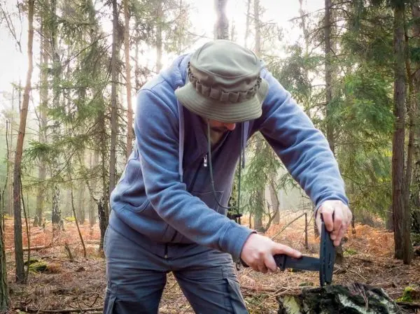 Messer schneidet Holzstück auf einem Baumstumpf im Wald