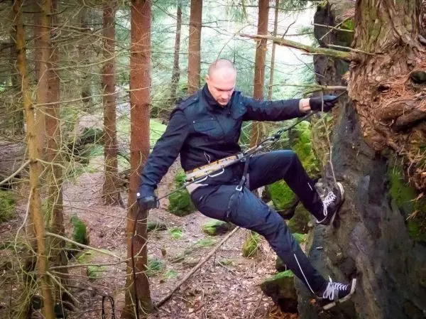 Person klettert an einer Felswand im Wald herunter