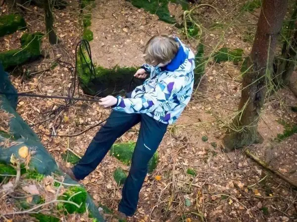 Person sichert sich mit einem Seil in einem Waldgebiet