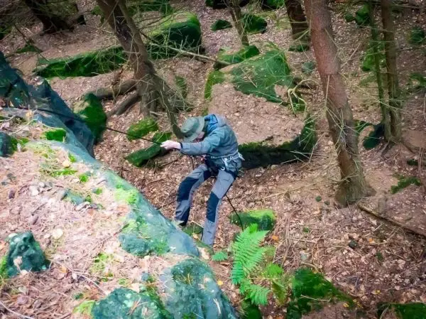Seilquerung an einer steilen Felswand im Wald mit Sicherungsseil