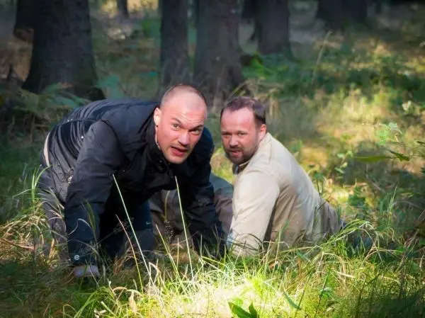 Zwei Personen kriechen durch hohes Gras im Wald