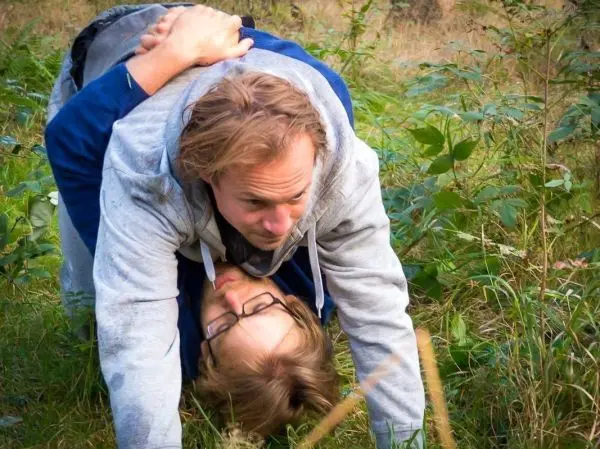 Zwei Personen liegen im Gras, eine Person stützt sich auf die andere