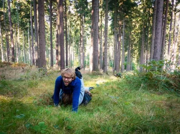 Zwei Personen liegen im Gras eines Waldes, eine Person auf der anderen