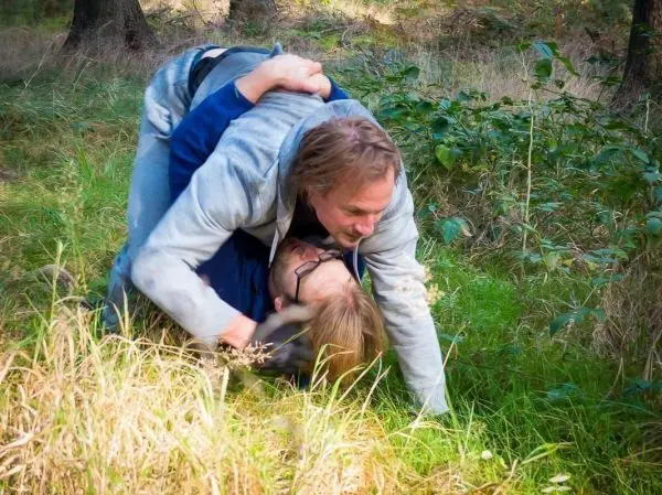 Zwei Personen ringen im Gras, einer liegt auf dem anderen